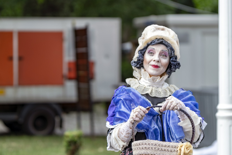 11 - A person dressed in theatrical costume with a blue ruffled garment and a delicate white lace collarfor for a performance